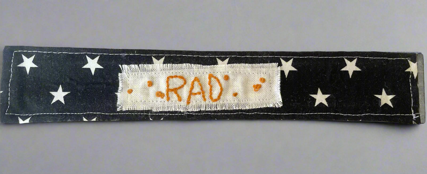 fabric slap bracelet with the word "rad" embroidered on it